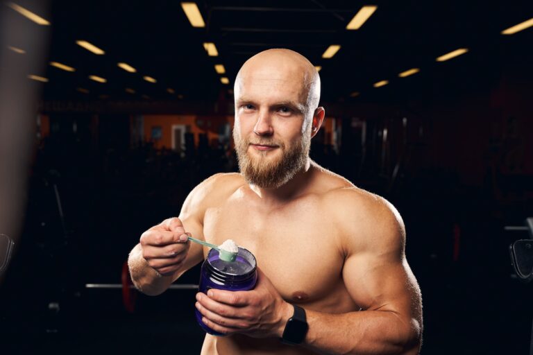 Muscular man hodling a spoonful of protein powder